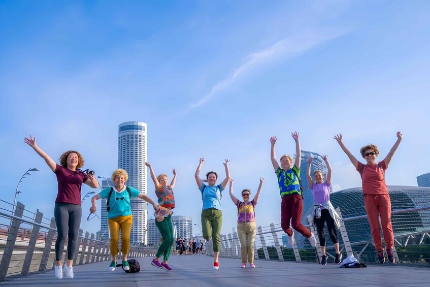 A group of people jumping on a bridge with city buildings in the background. 1