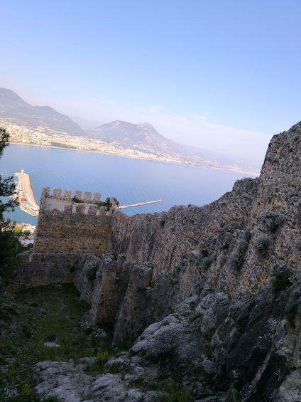 A coastal cityscape with a historic stone fort overlooking a calm sea. 3