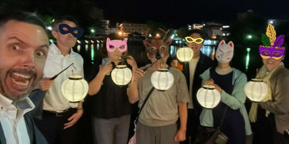 A group of people holding paper lanterns at night. 4