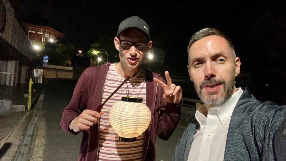 Two people taking a selfie with a street lamp and a building in the background. 3