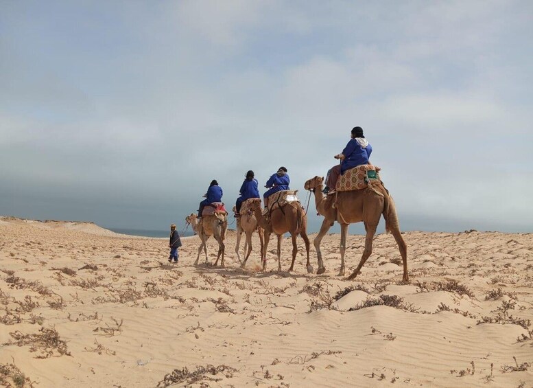 A group of people riding camels across a desert landscape. 2