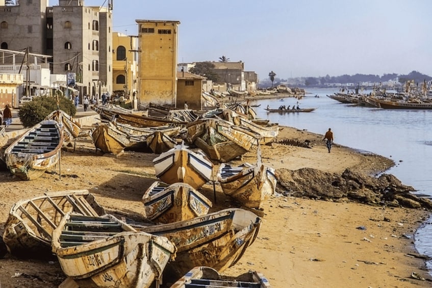 A riverside with boats docked on the shore and a building in the background. 2