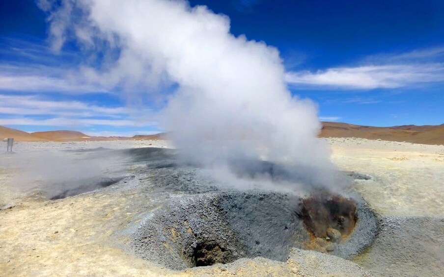 A geothermal area with steam rising from a crater. 2