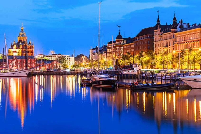 A waterfront cityscape with illuminated buildings, a prominent church, and boats docked along the quay. 2