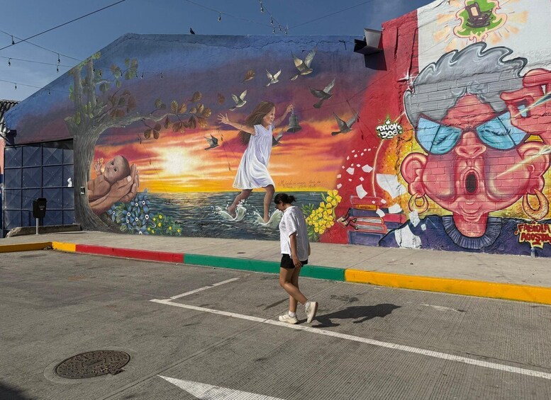 A mural with a sunset, flying birds, and a woman walking. 3