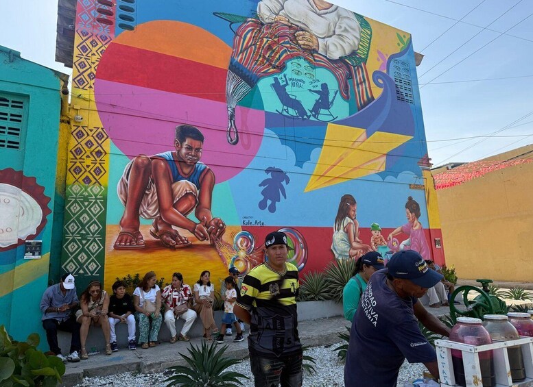 A vibrant mural with a central figure, surrounded by people and a street vendor. 2