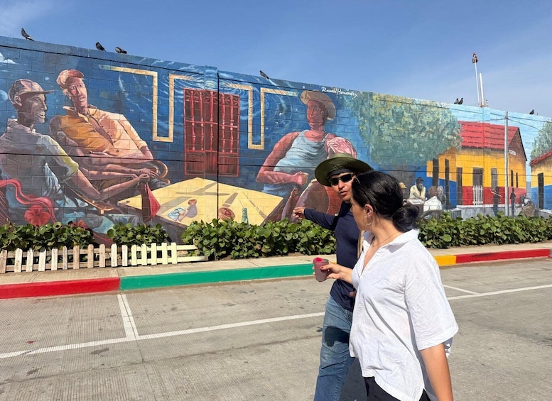 A mural with people and a fence in the foreground. 1