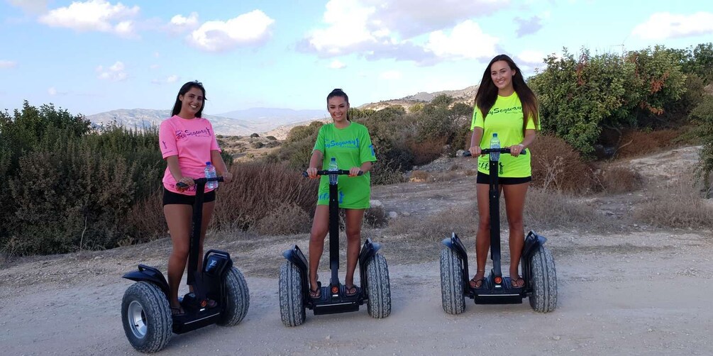 Three people on segways on a dirt path with hills and sparse vegetation in the background. 5