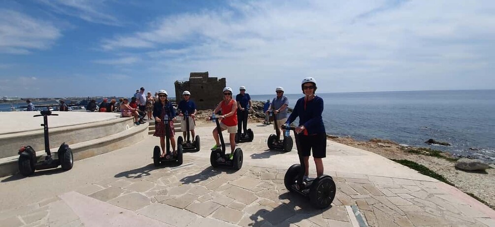People riding segways on a stone pathway by the sea. 3