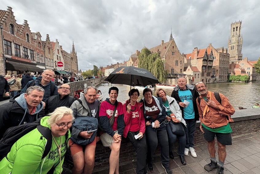 A group of people posing in front of historic buildings by a canal. 1