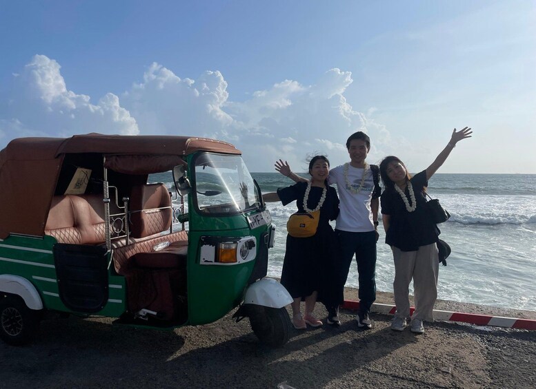 En grön, automatisk rickshaw står parkerad vid havet och folk står bredvid den. 3