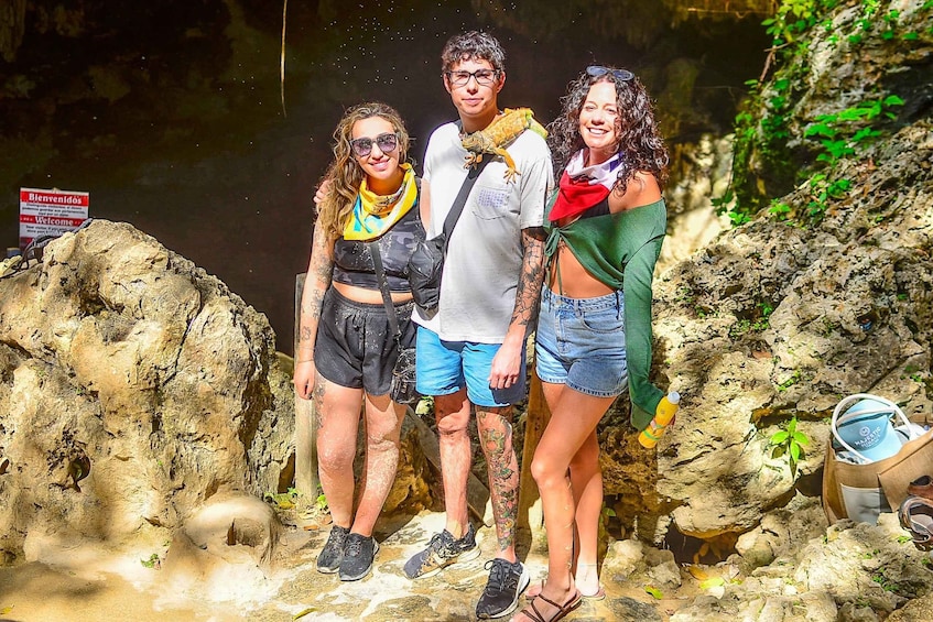 Three people standing on a rocky terrain with a sign in the background. 5