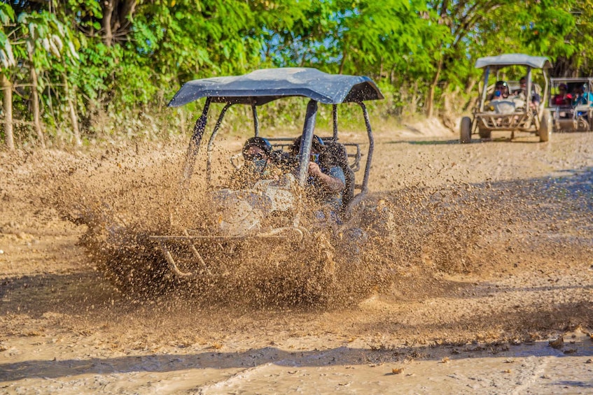 A vehicle driving through a dusty area, kicking up a cloud of dust. 2