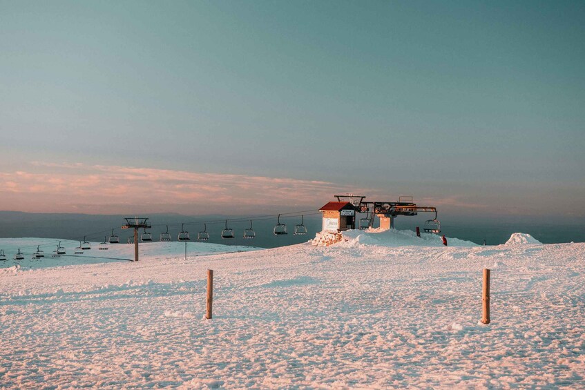 A snow-covered ski slope with a chairlift and a small building. 4