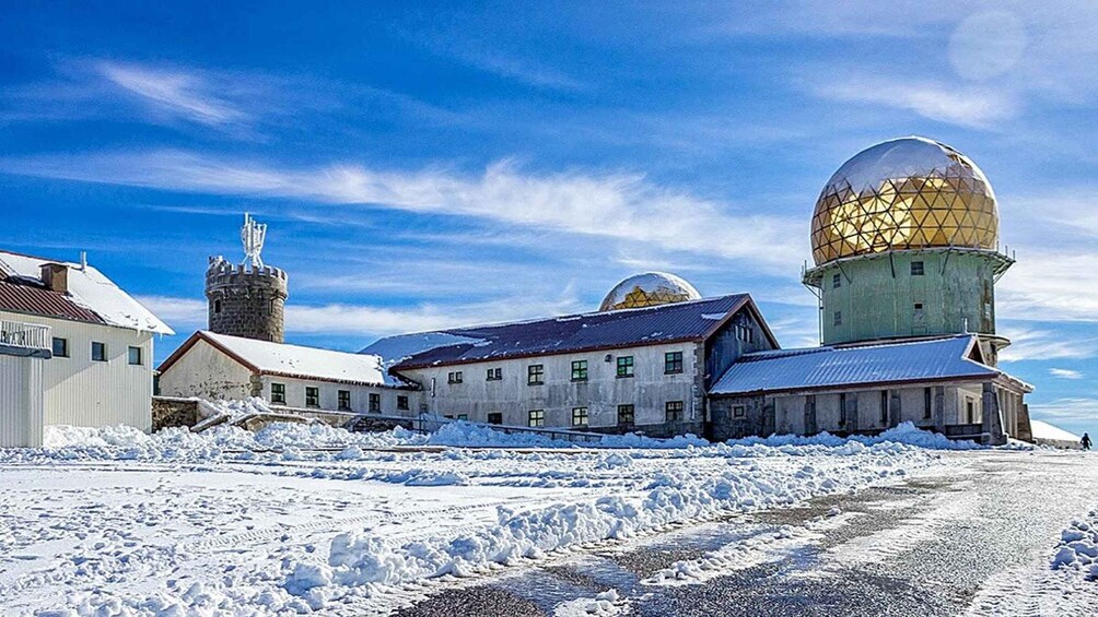 A snow-covered landscape with buildings, including a tower and a dome structure. 2