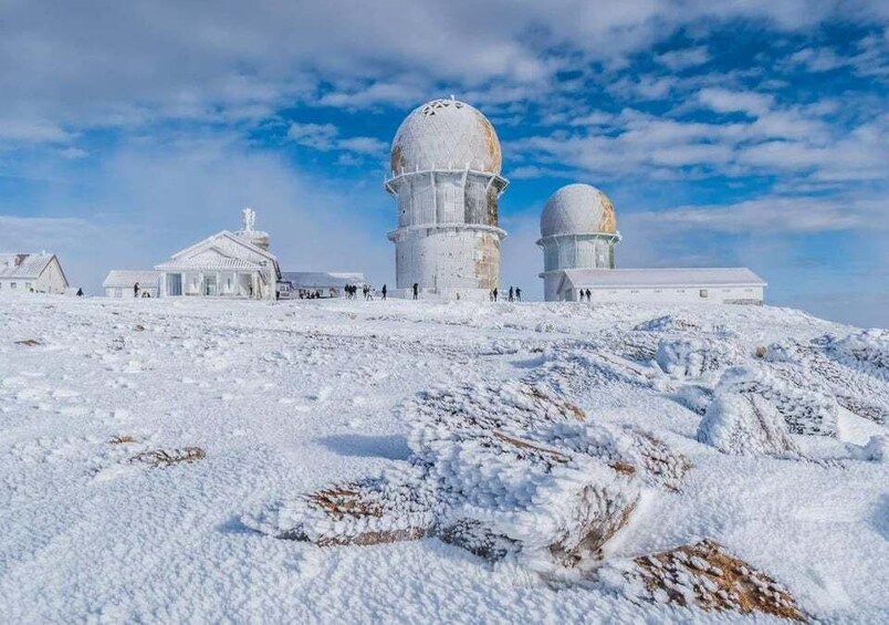 A snow-covered observatory with domed structures and a clear sky. 1