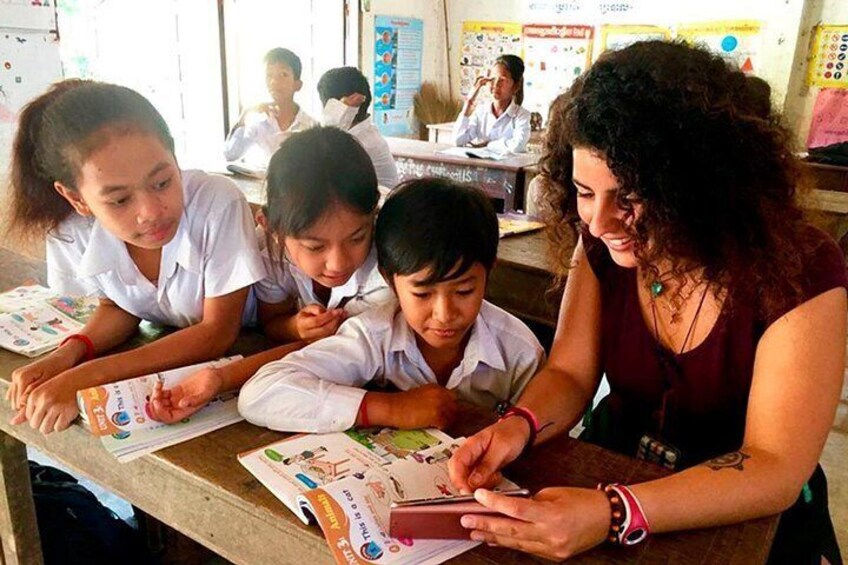 Kinder und ein Erwachsener im Klassenzimmer, die beim Lesen und Schreiben aktiv sind. 5