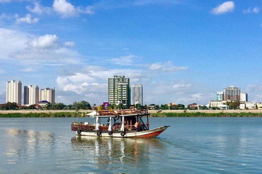 Ein Boot auf einem ruhigen Fluss, im Hintergrund die Skyline einer Stadt. 3