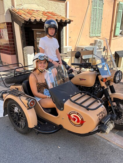 A person in a sidecar motorcycle with a sidecar, a helmet, and a white shirt. 1
