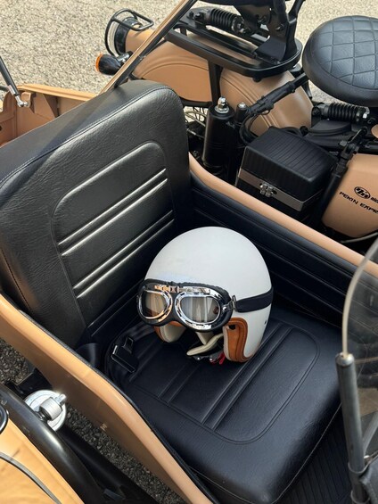 A vintage car interior with a white helmet and goggles on the seat. 5