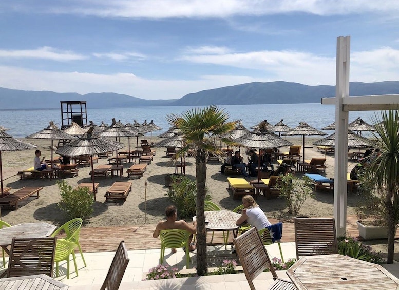 A beachside café with outdoor seating and umbrellas, overlooking the sea. 3