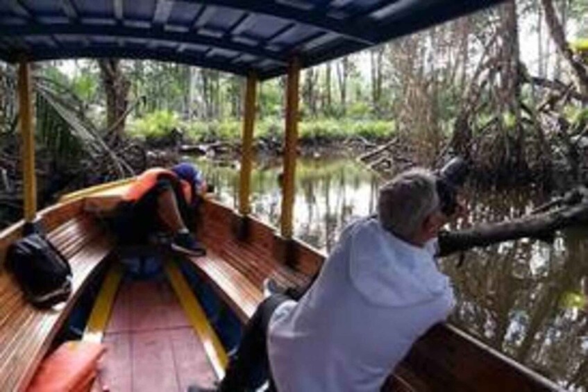 A wooden boat on a calm river surrounded by dense vegetation. 4