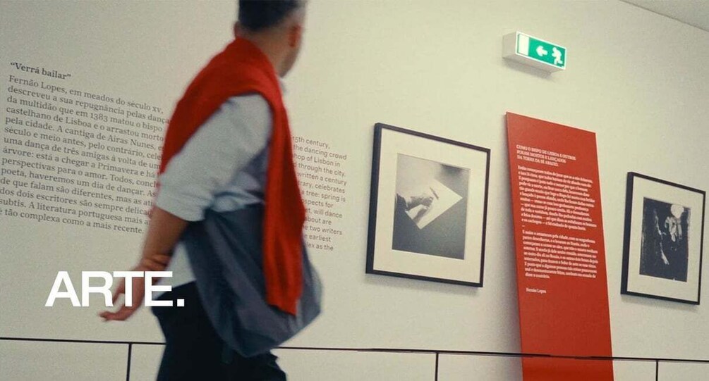 A person walking past an art exhibit with framed pictures and informational text. 5