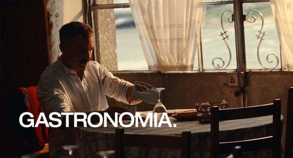 A person pouring a drink into a glass at a table by a window with curtains. 4