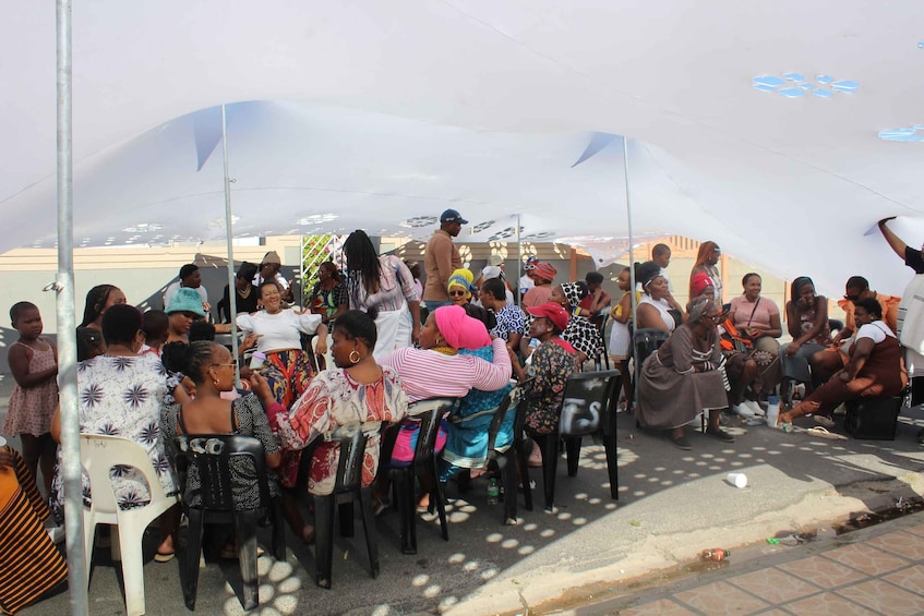 A group of people seated under a large tent on a street. 1