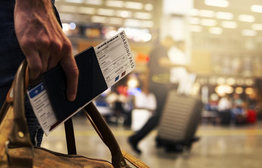 A person holding a boarding pass and a smartphone. 3