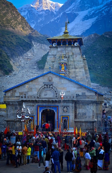 A stone temple with a blue roof and a golden spire, surrounded by a crowd of people. 5