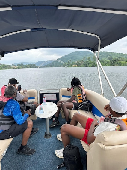 A group of people on a boat with a table and a sign warning about the boat's door. 1