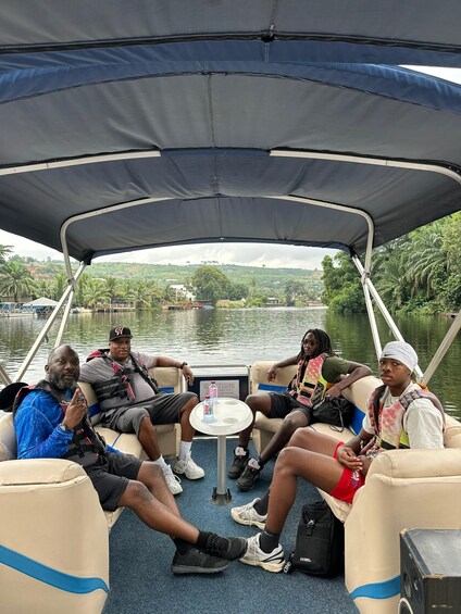 A group of people on a boat with a canopy, surrounded by water and greenery. 5