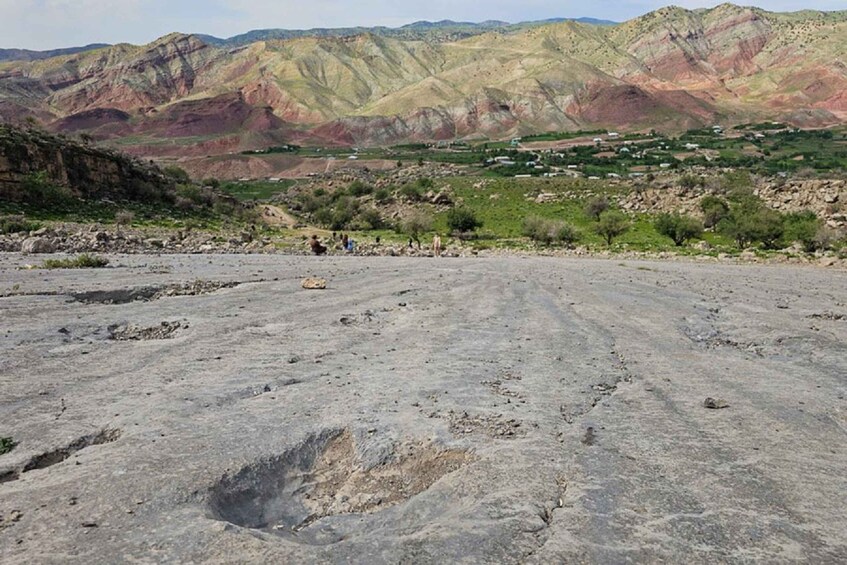 A barren landscape with a large crater, distant hills, and sparse vegetation. 1