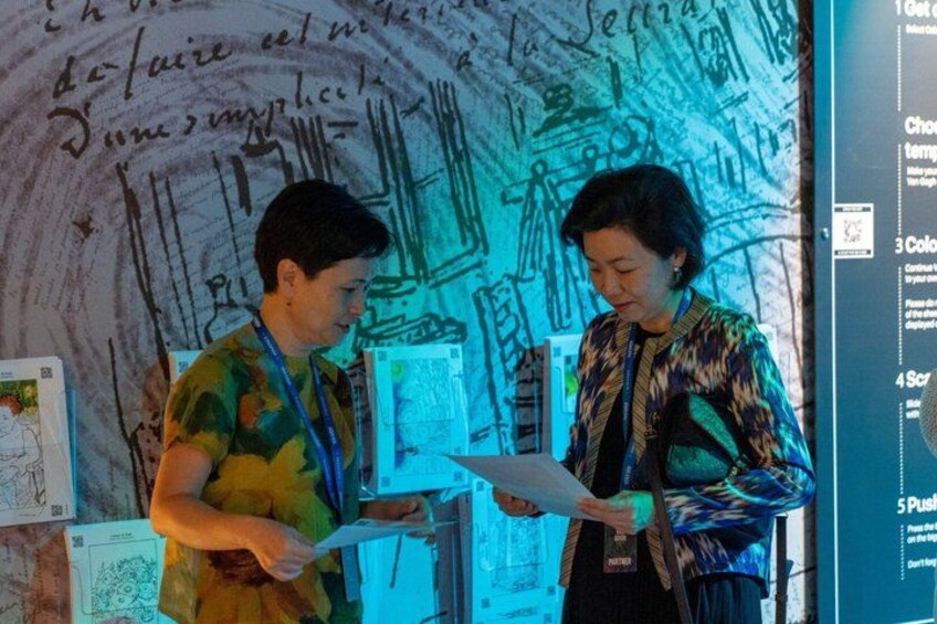 Two people discussing in front of a wall with drawings and text. 3