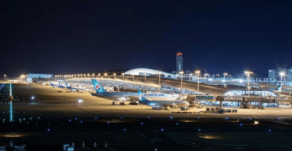 A nighttime airport scene with multiple airplanes parked, illuminated by overhead lights. 2