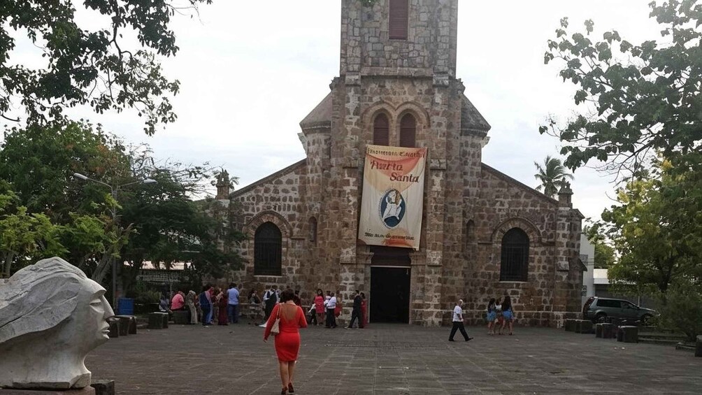 A stone church with a tall bell tower and a banner reading 'Avenida Santa.' 2