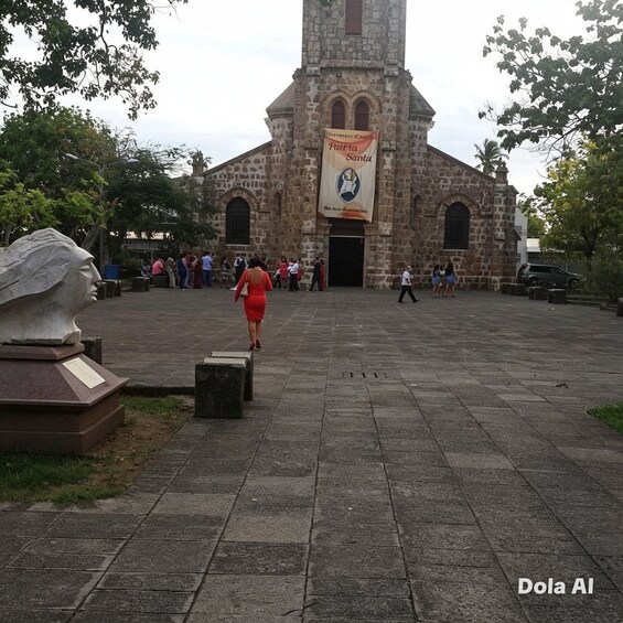 A stone church with a bell tower, a statue, and a banner. 2