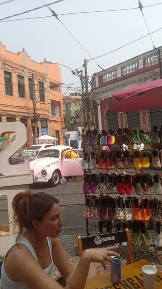 A street scene with a vintage car, a shoe kiosk, and buildings in the background. 5