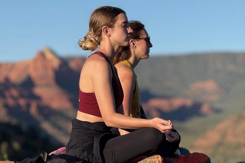 Two people sitting on a blanket with a mountainous landscape in the background. 3