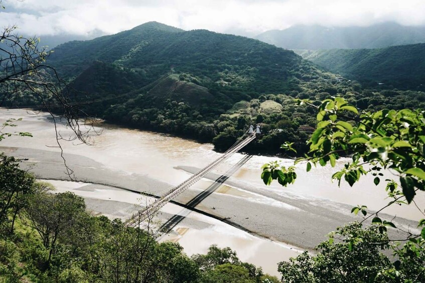 A suspension bridge over a river, surrounded by lush green hills. 1