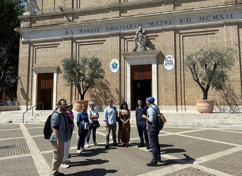 A group of people standing in front of a building with inscriptions and a statue. 1