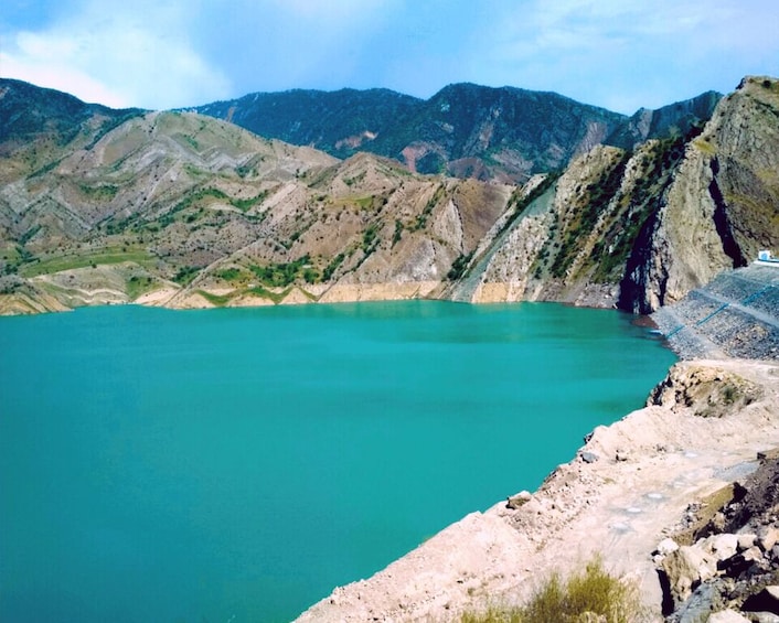 A turquoise lake surrounded by rugged mountains and a rocky shoreline. 3