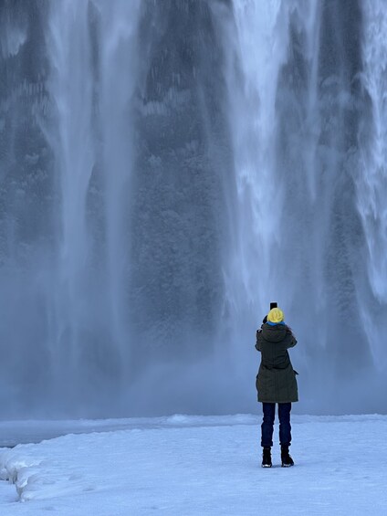 A person taking a photo of a waterfall. 4