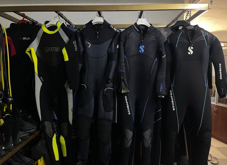 A rack of wetsuits with various brands and designs. 2