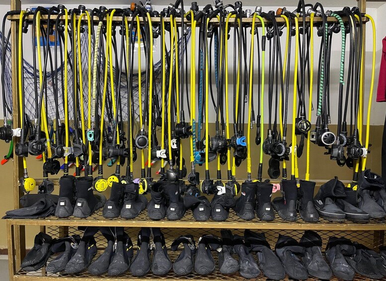 A rack of fishing rods and a shelf of black boots. 4