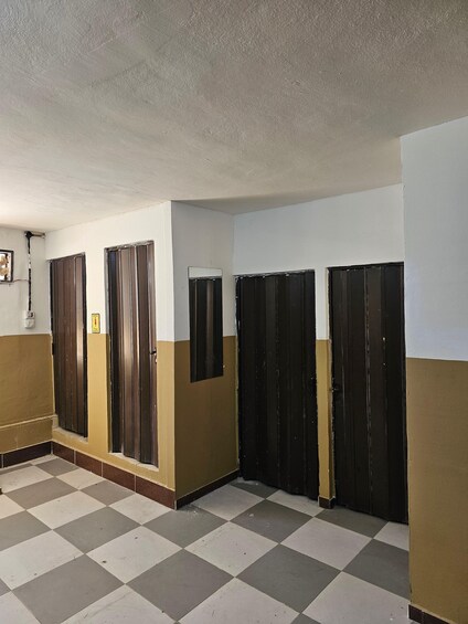 A hallway with checkered flooring, beige walls, and black doors. 5