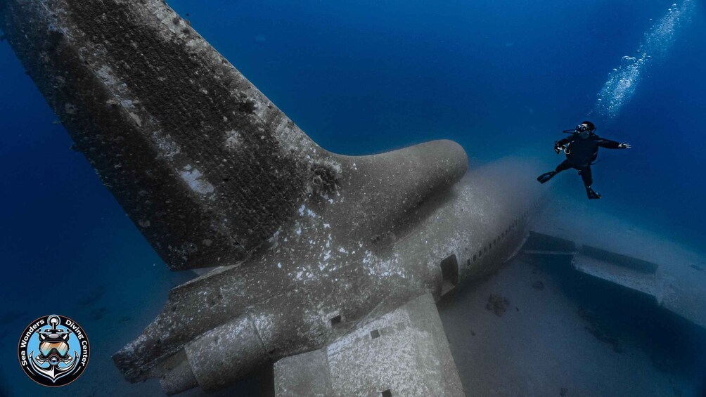 A diver exploring an underwater structure with a large, weathered concrete formation. 3