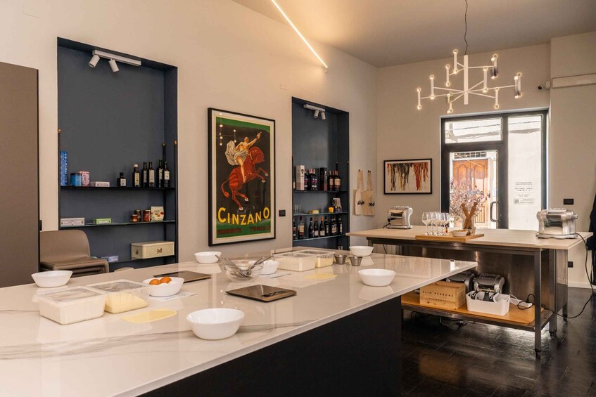 A modern kitchen with a marble island, wine bottles, and a poster of a woman on a horse. 1