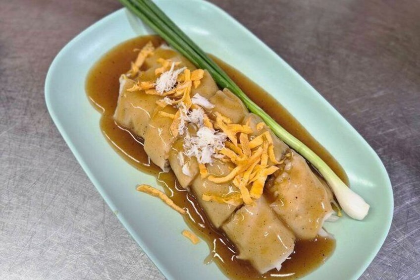 A dish with dumplings in a light green bowl, garnished with shredded carrots and green onions, and accompanied by a green chive. 5